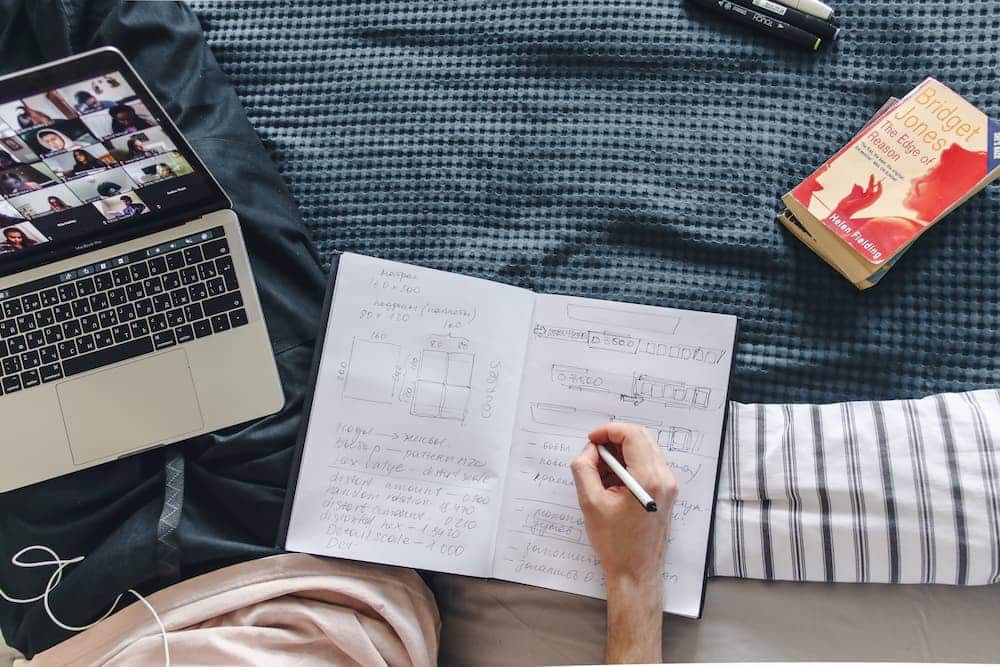 persona che prende appunti facendo formazione online persona seduta sul divano che prende appunti mentre fa formazione online