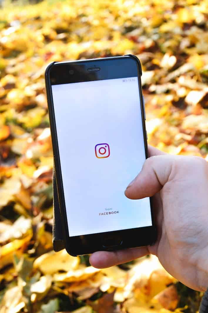 smartphone con schermata di accesso a instagram mano che regge uno smartphone e apre l'app di Instagram